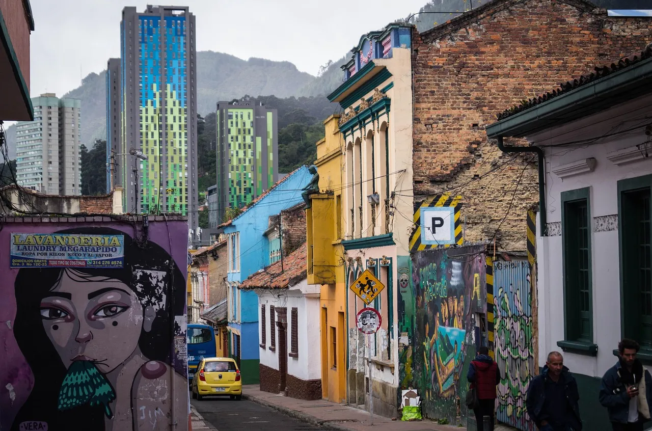 Una calle empinada de casas pintadas y murales bajo torres de apartamentos