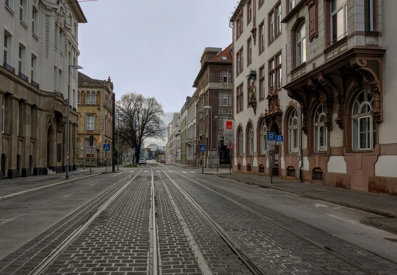 Eine leere Straße mit Straßenbahngleisen zwischen alten Fassaden