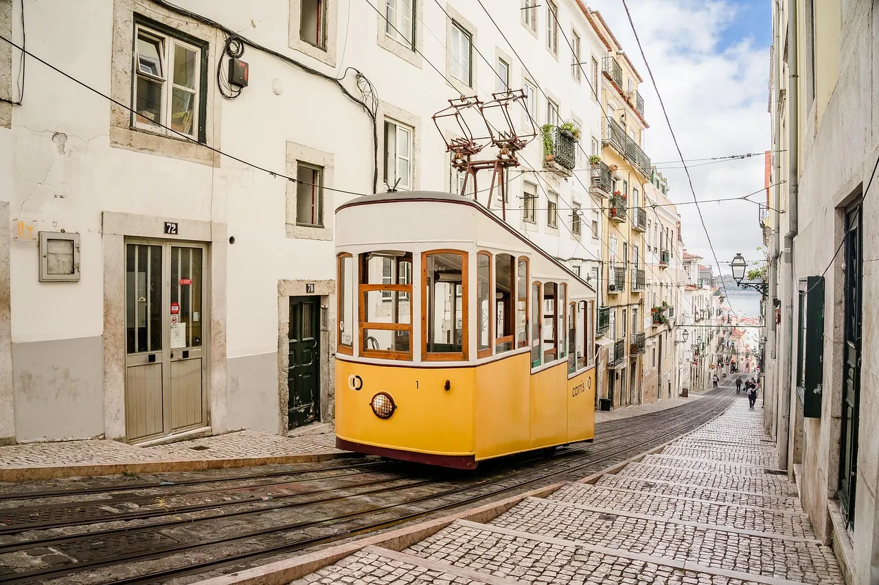 Un tranvía amarillo sube por una calle estrecha de Lisboa