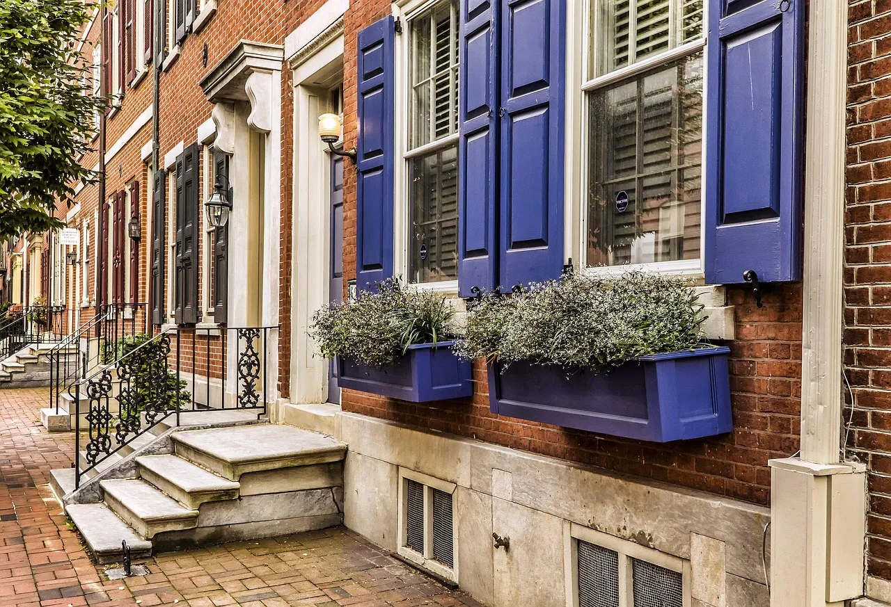 Una casa adosada de ladrillo con contraventanas azules y jardineras